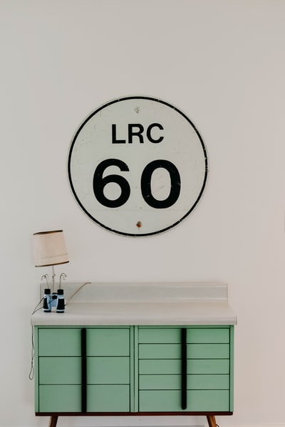 White and green wooden desk, close to the LRC England 60 wall panels, with a brown shade
